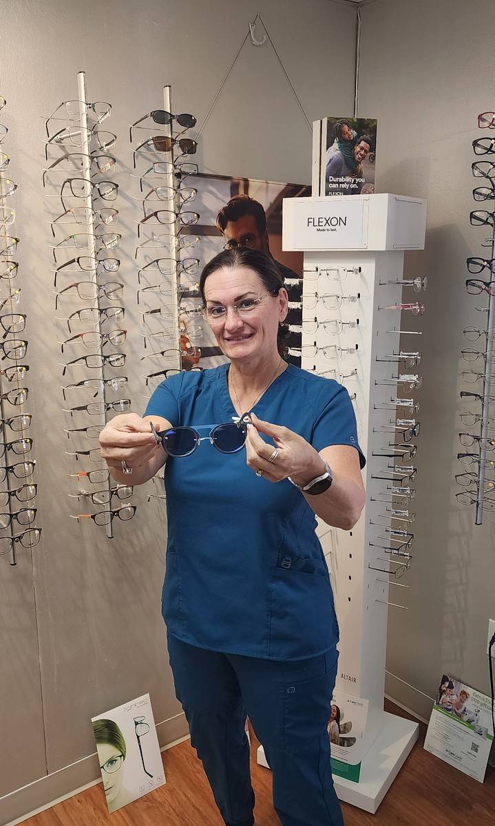 Andrea Baker holding a pair of prescription sunglasses at her optical shop in Burnet, TX
